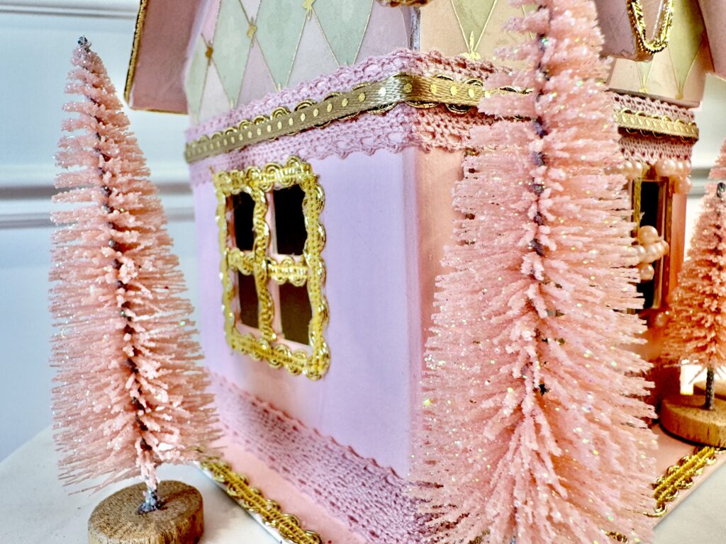 Pink and gold Valentine miniature putz house made from paper mache, ribbon, paper and glitter with pink bottle brush trees for accents.