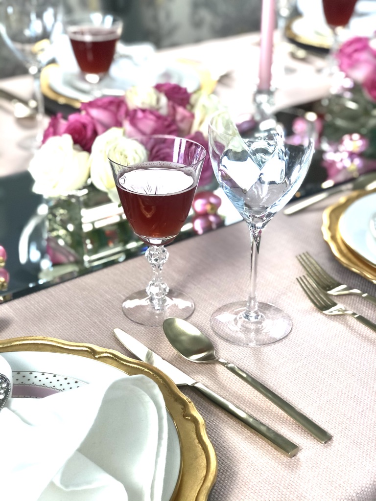 A soft pink table cloth from a woven upholstery weight fabric blends beautifully with gold utensils and cut drink glasses.