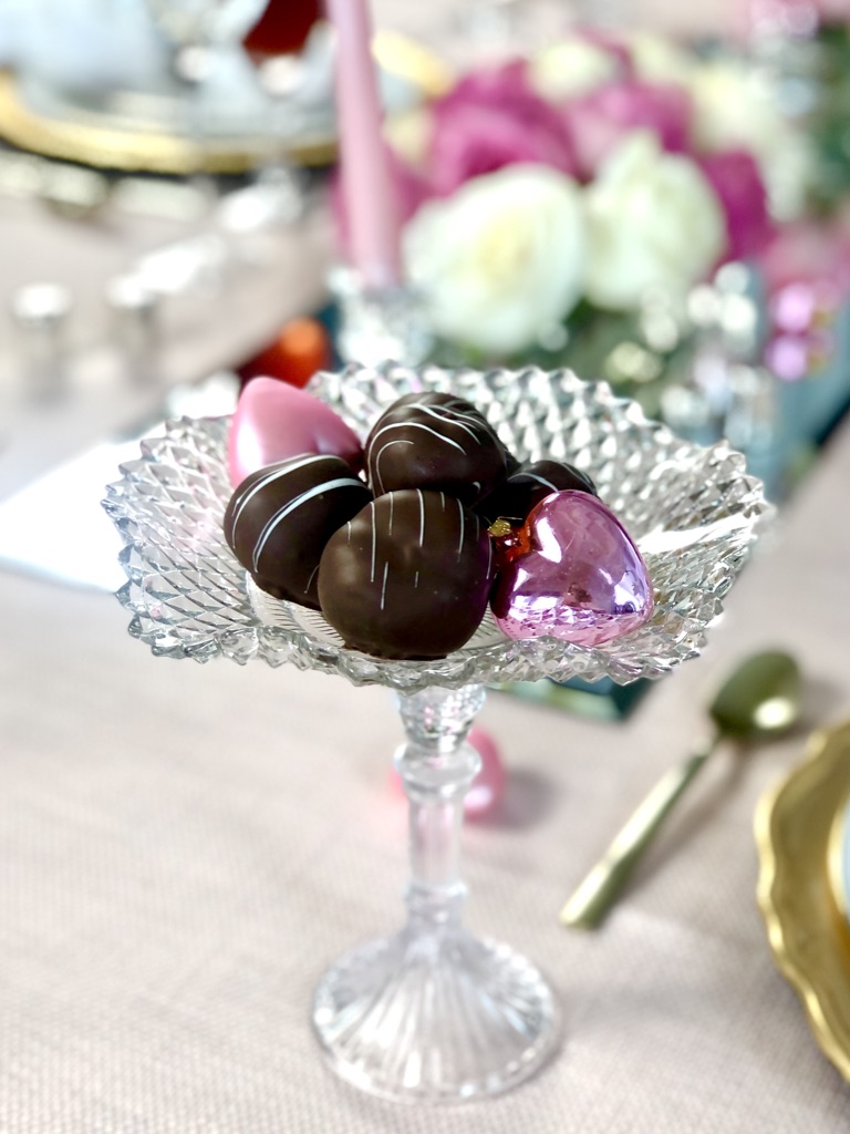 Valentines chocolates displayed on raised, cut glass candy dishes.