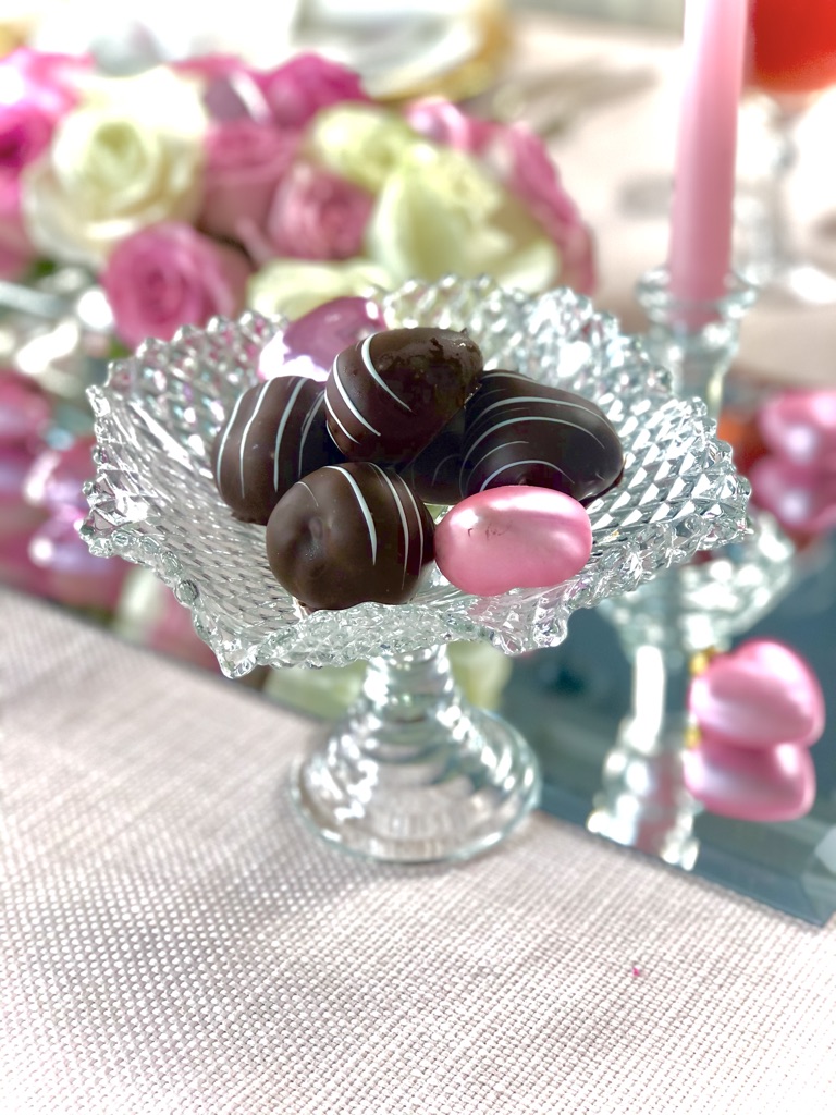 Valentines chocolates displayed on raised, cut glass candy dishes.