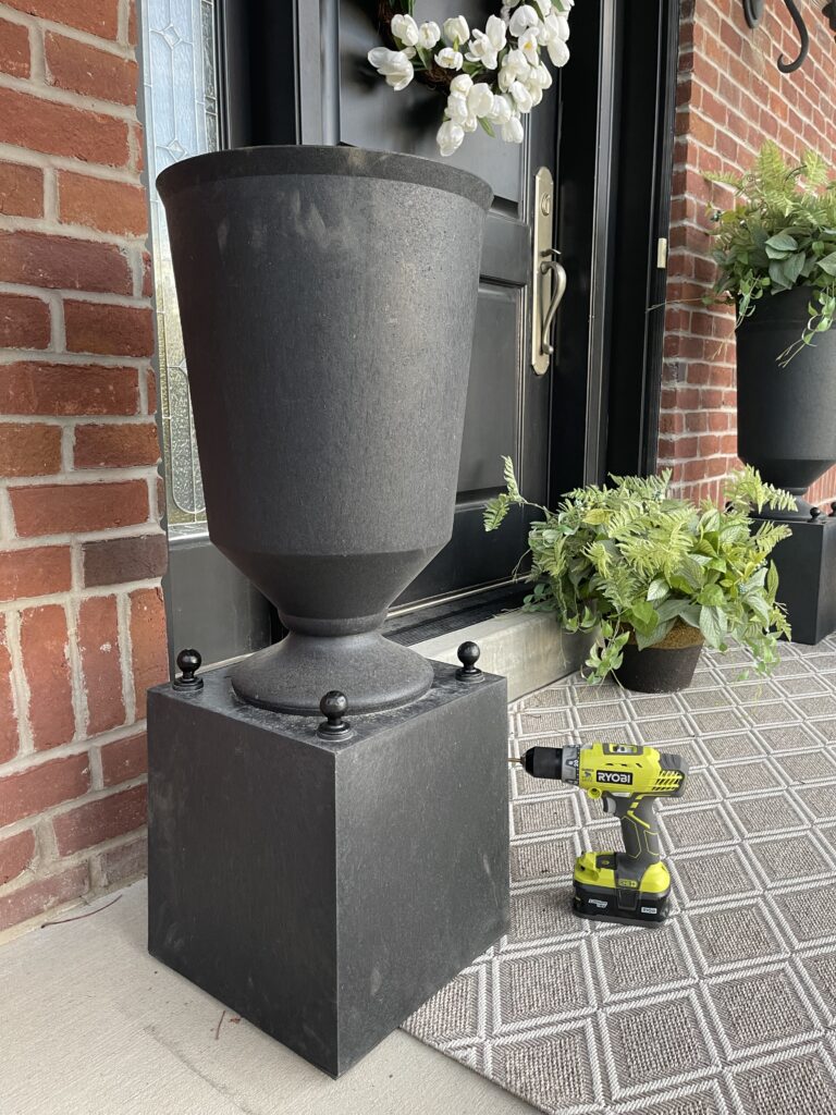 Tall black Estate Style Planter created from two pots. A square planter is turned upside down to create a base, with a round, cylindrical planter placed on top. Stacking the two together creates the illusion of a single, large planter.