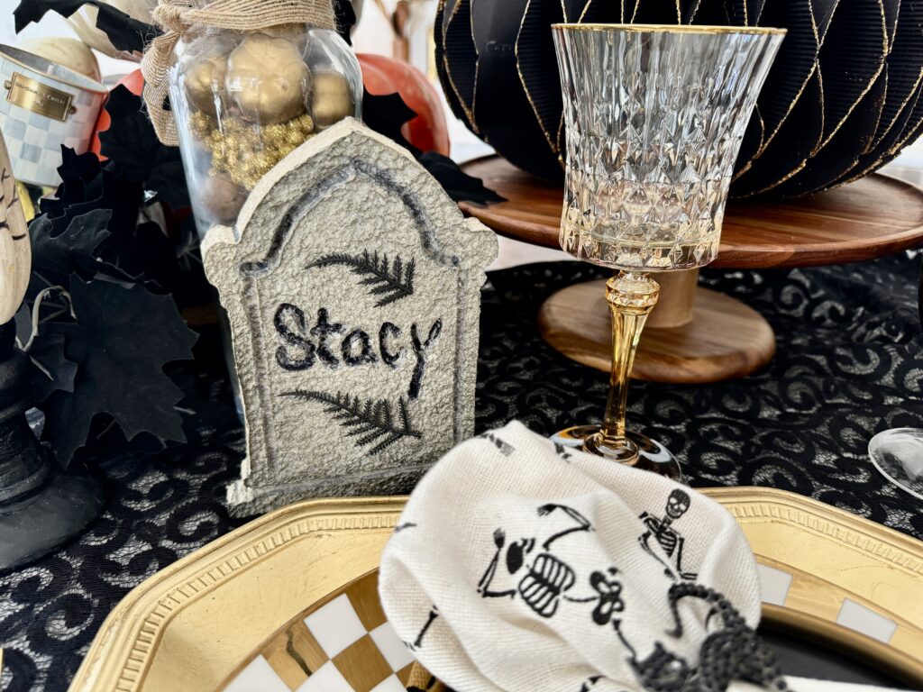 Headstone place cards for a sophisticated Halloween tablescape. The black and gold settings, along with a blingy black cat napkin ring offset the stone looking gravestone carved with each guests name.